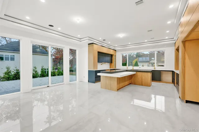 a large white kitchen with large windows and a fireplace