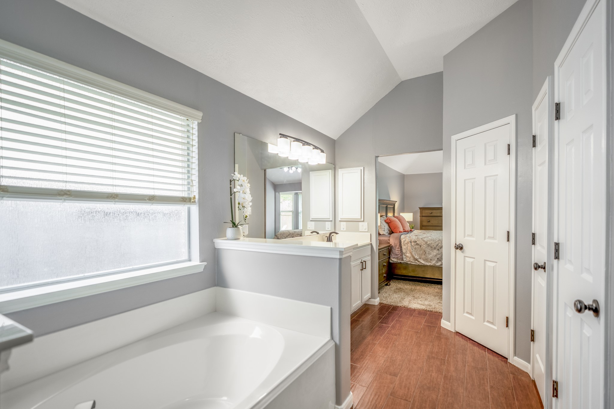 3411 Utah Beach Court Spring, TX 77388 - Photo 25 of 50 Looking back through the primary bath, the layout connects each piece of the suite with an easy, practical flow. The soaking tub sits beneath the window, the long vanity runs along the opposite side, and the doorway ahead leads back into the primary bedroom, keeping the bath, closet, and bedroom all comfortably connected.