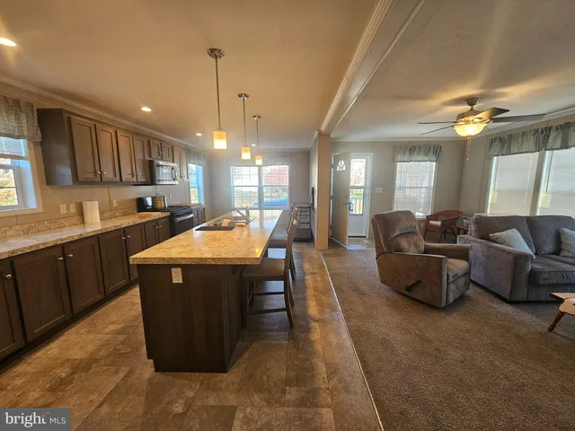 a kitchen with stainless steel appliances granite countertop a sink dishwasher a living room with couches and kitchen view