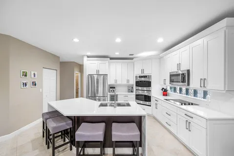 a kitchen with stainless steel appliances a dining table chairs and a refrigerator