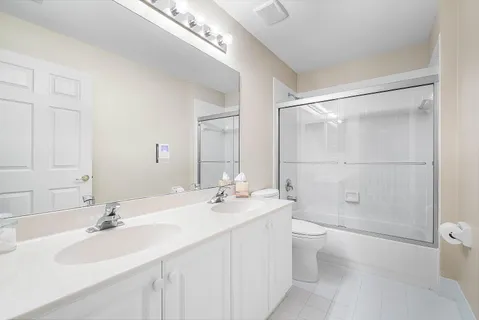 a bathroom with a double vanity sink toilet mirror and shower