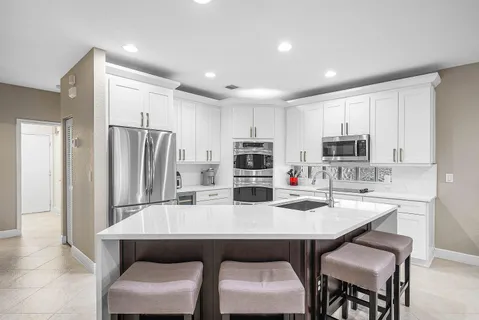 a kitchen with stainless steel appliances a dining table chairs refrigerator and microwave