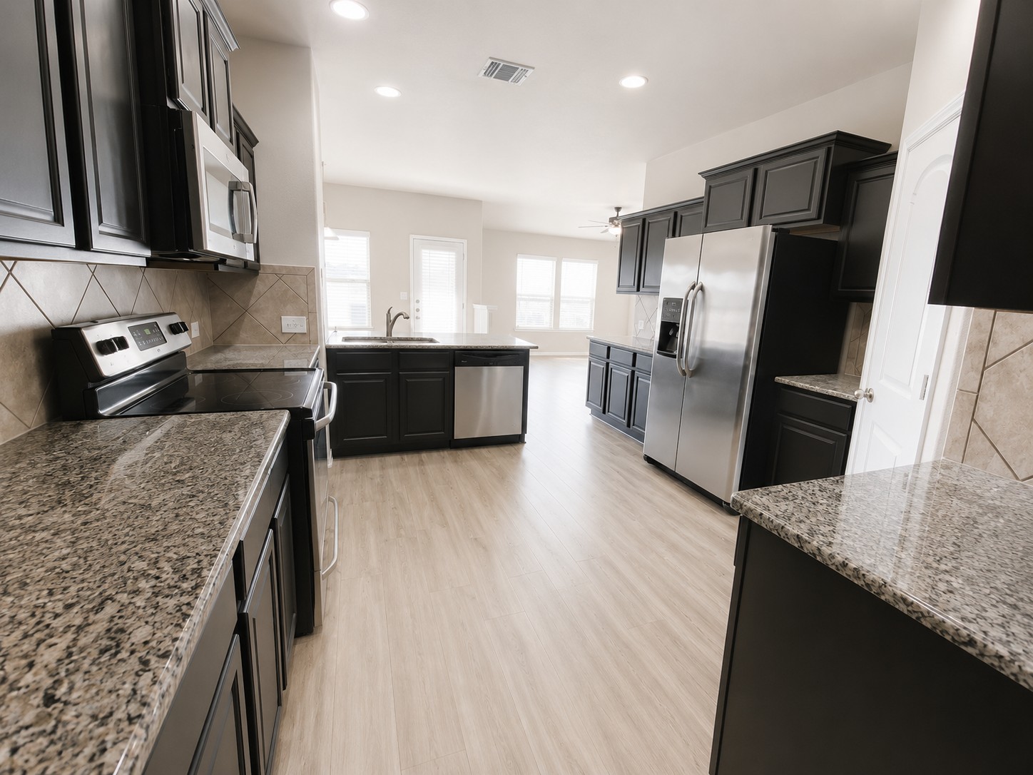 228 Avalanche Avenue Georgetown, TX 78626 - Photo 4 of 16 a kitchen with stainless steel appliances granite countertop a refrigerator a sink a stove a microwave and wooden cabinets