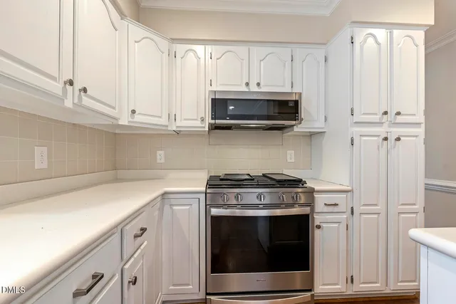 a kitchen with white cabinets and stainless steel appliances
