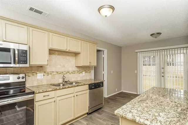 a kitchen with stainless steel appliances granite countertop a stove a sink and a refrigerator