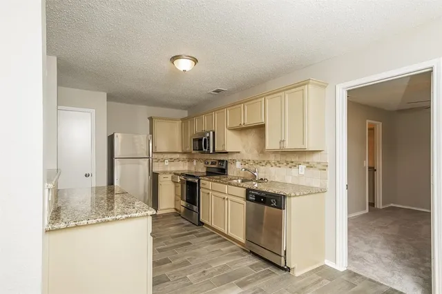 a kitchen with stainless steel appliances granite countertop a stove top oven a refrigerator and a sink