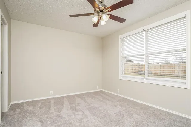 an empty room with a window and a fan