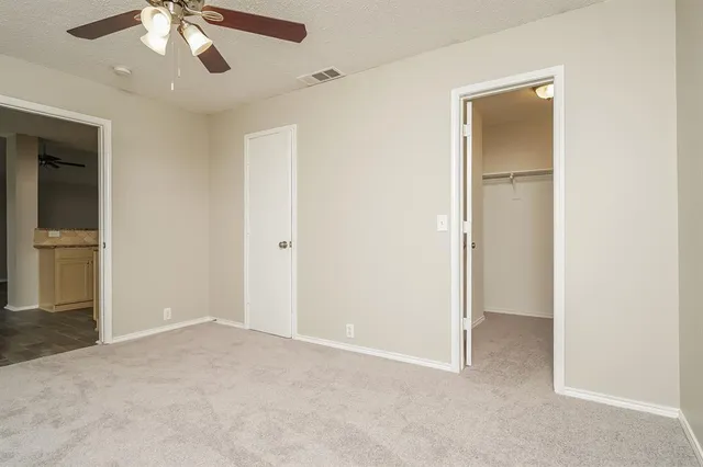 an empty room with closet and a ceiling fan