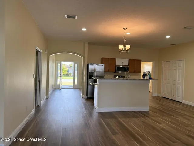 a view of a kitchen with kitchen island wooden floor and living room