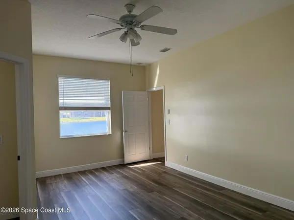 an empty room with wooden floor chandelier fan and windows