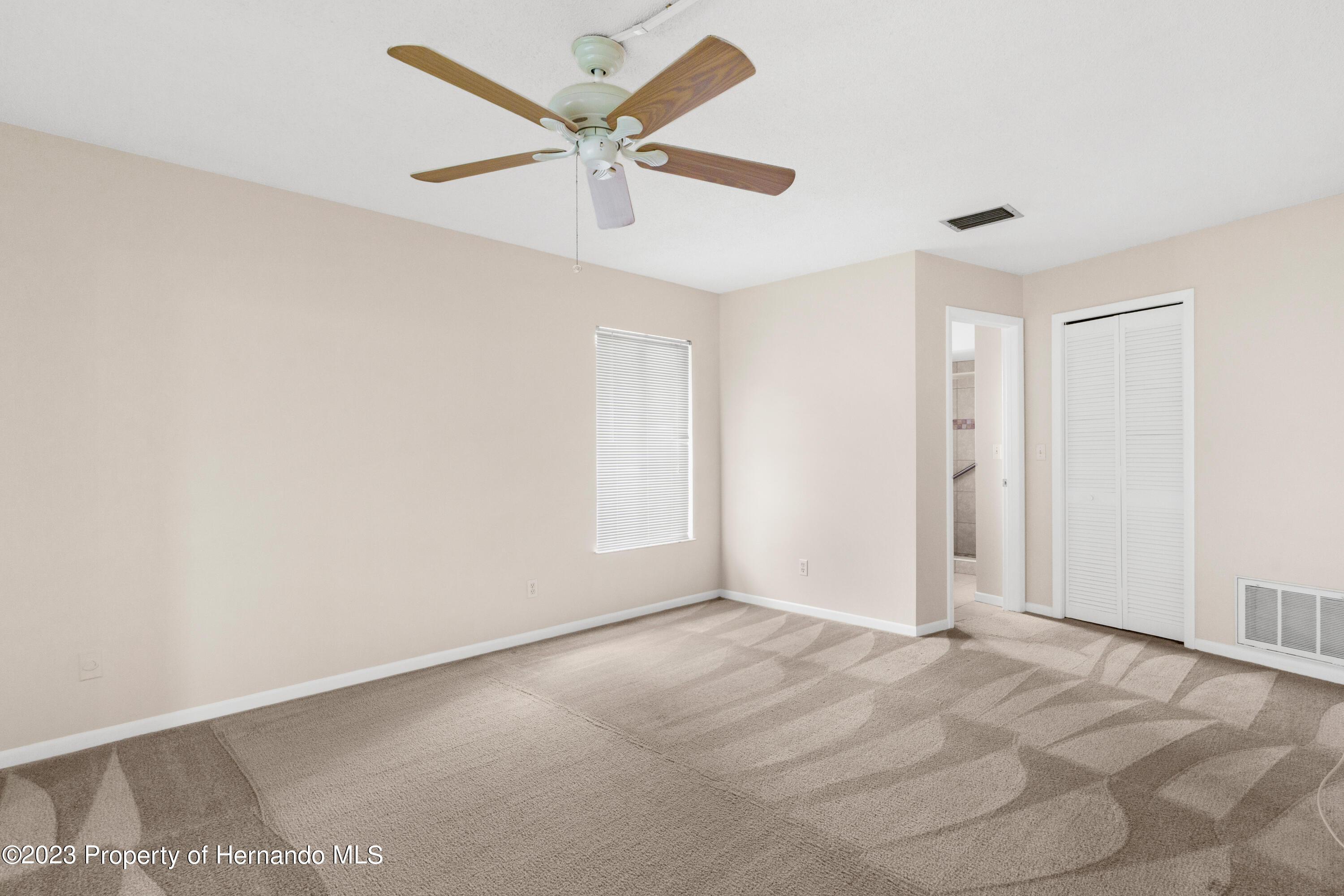 10241 Bedford Road Spring Hill, FL 34608 - Photo 12 of 32 an empty room with a ceiling fan and a window