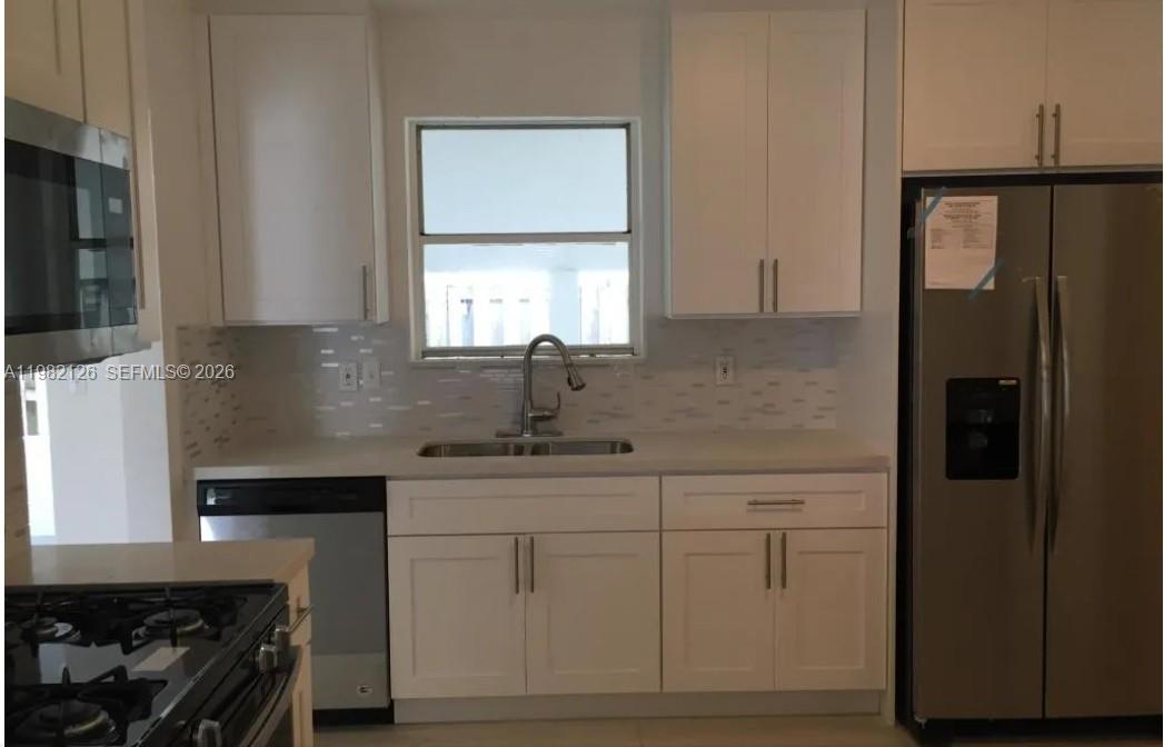 320 Southwest 7th Court Hallandale Beach, FL 33009 - Photo 4 of 5 a kitchen with stainless steel appliances granite countertop a refrigerator and a stove