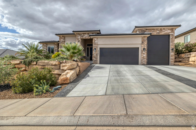 2985 West Sesia Way St. George, UT 84770 - Photo 1 of 1 Prairie-style house featuring an attached garage, stone siding, stucco siding, and driveway