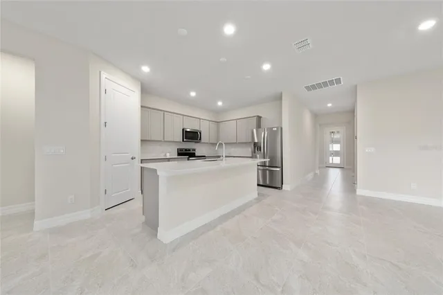 a view of a kitchen with refrigerator and white cabinets