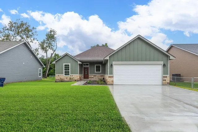 a front view of house with yard and trees in the background