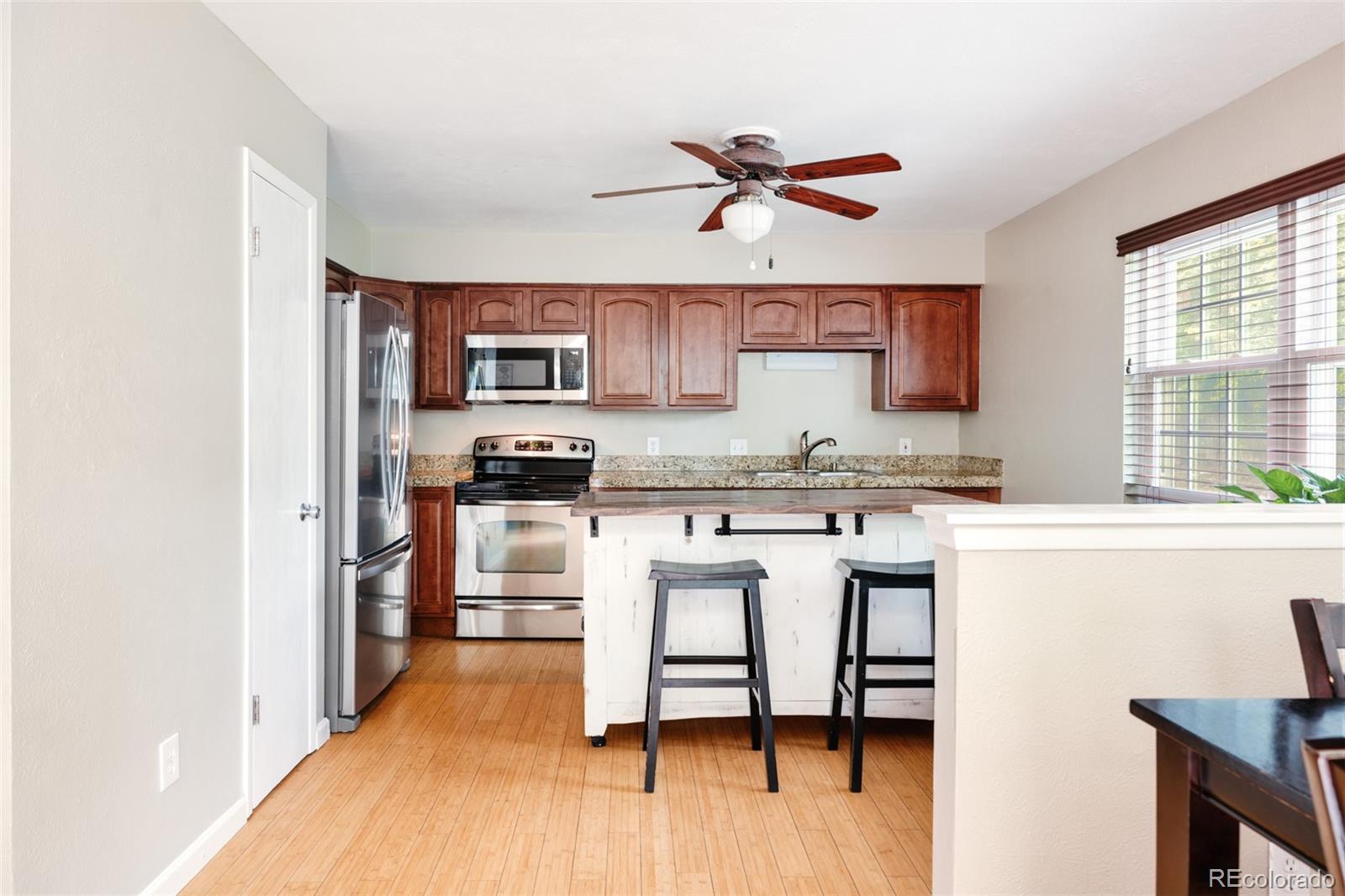 7448 West Roxbury Place Littleton, CO 80128 - Photo 6 of 30 a kitchen with a refrigerator a stove a sink and white cabinets with wooden floor