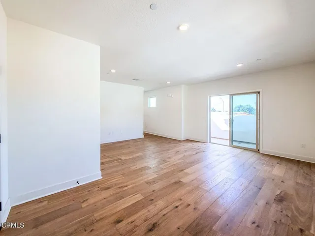a view of an empty room with wooden floor and window