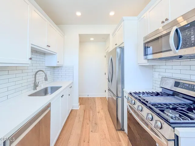 a kitchen with stainless steel appliances granite countertop a sink stove refrigerator and cabinets