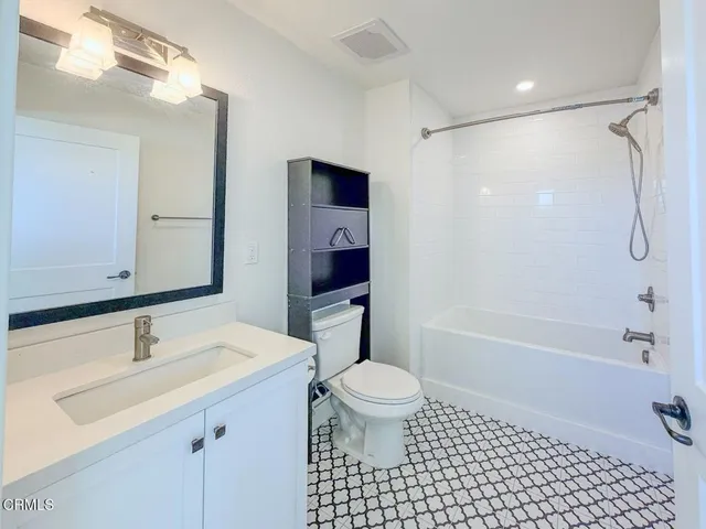 a bathroom with a sink a toilet a mirror and shower