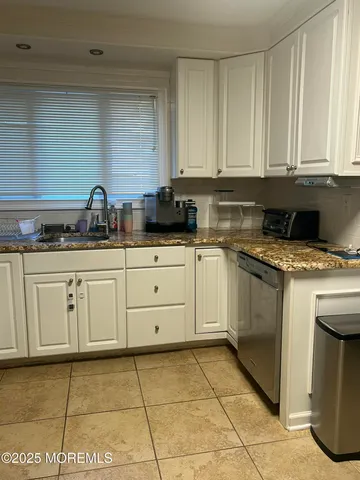 a kitchen with granite countertop white cabinets sink and stainless steel appliances
