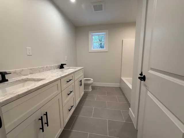 a bathroom with a double vanity sink a toilet and a tub