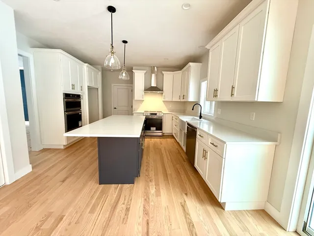 a large kitchen with granite countertop a large counter top space a sink stainless steel appliances and cabinets