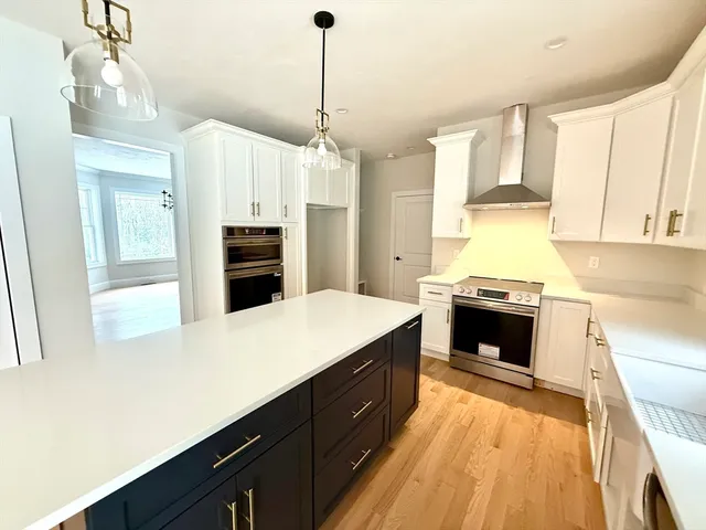 a kitchen with stainless steel appliances a stove top oven a sink dishwasher a refrigerator and a dining table with wooden floor