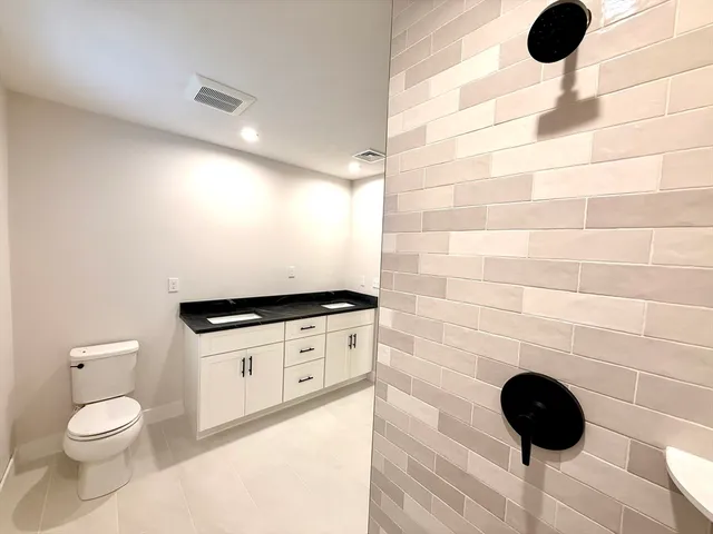a bathroom with a granite countertop toilet a sink and a mirror