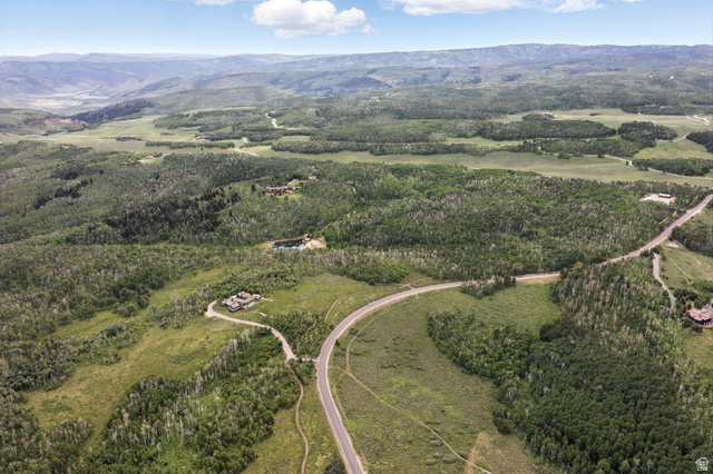 1555 North Wolf Creek Ranch Road, Unit 11 Heber City, UT 84036 - Photo 8 of 9 Expansive aerial landscape featuring a winding paved road, lush green forests, distant mountainous terrain, and scattered residential properties