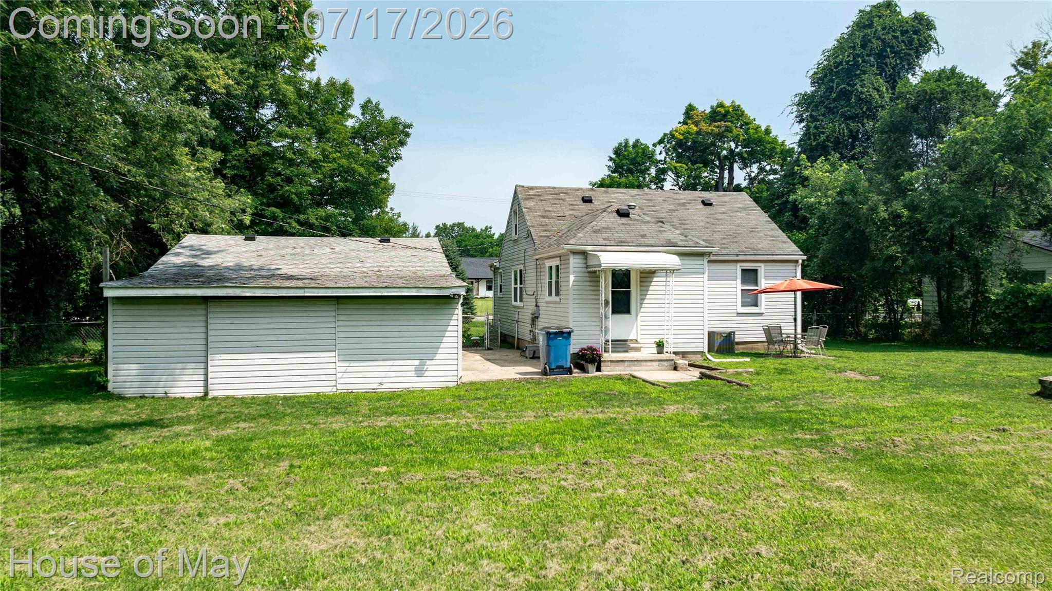45247 Bemis Road Belleville, MI 48111 - Photo 22 of 28 Spacious rear yard featuring a detached garage with horizontal siding, a patio area, and mature perimeter trees