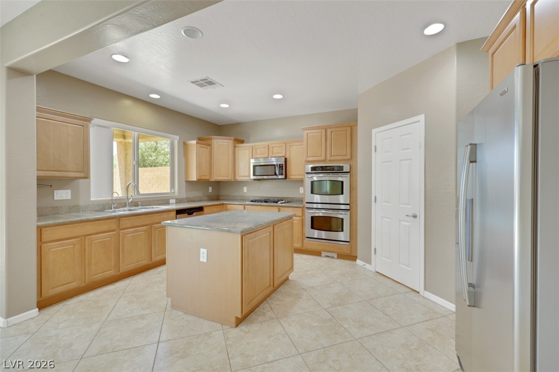 2501 Bechamel Place Henderson, NV 89044 - Photo 6 of 50 A well-lit kitchen with light wood cabinetry, an island, and modern appliances.