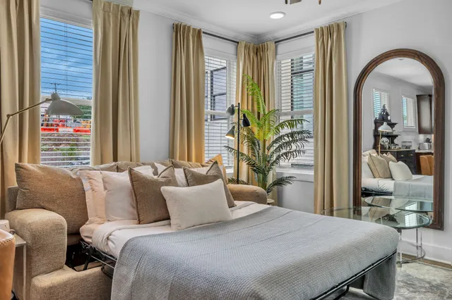 a bedroom with a bed and a large mirror next to a window