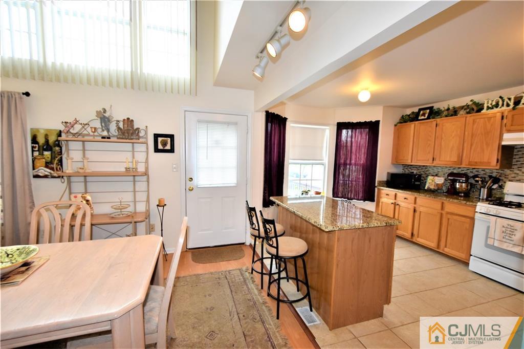 304 Hawthorne Road North Brunswick, NJ 08902 - Photo 11 of 25 a kitchen with stainless steel appliances granite countertop a sink a stove a refrigerator a dining table and chairs with wooden floor
