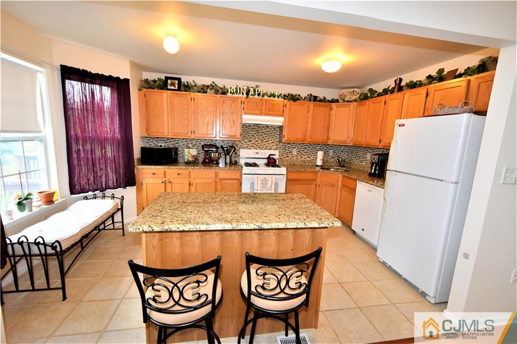 304 Hawthorne Road North Brunswick, NJ 08902 - Photo 9 of 25 a kitchen with granite countertop a refrigerator a stove and a dining table with wooden floor