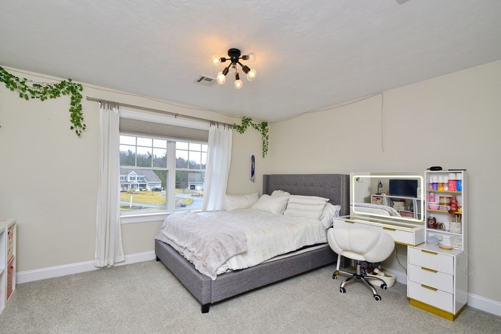 5 Tailwind Circle Norfolk, MA 02056 - Photo 22 of 40 a bedroom with a bed and a chandelier