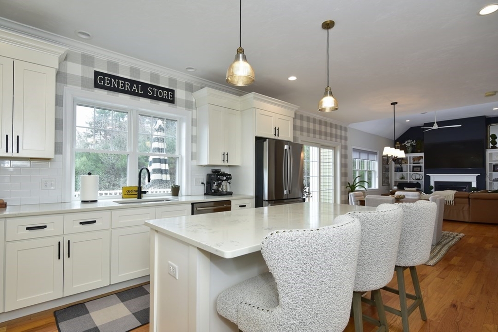 5 Tailwind Circle Norfolk, MA 02056 - Photo 9 of 40 a kitchen with stainless steel appliances kitchen island granite countertop a stove a sink a refrigerator a counter space and dining table with wooden floor