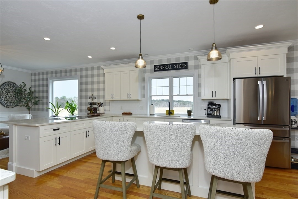 5 Tailwind Circle Norfolk, MA 02056 - Photo 10 of 40 a kitchen with stainless steel appliances granite countertop a kitchen island a table and chairs in it