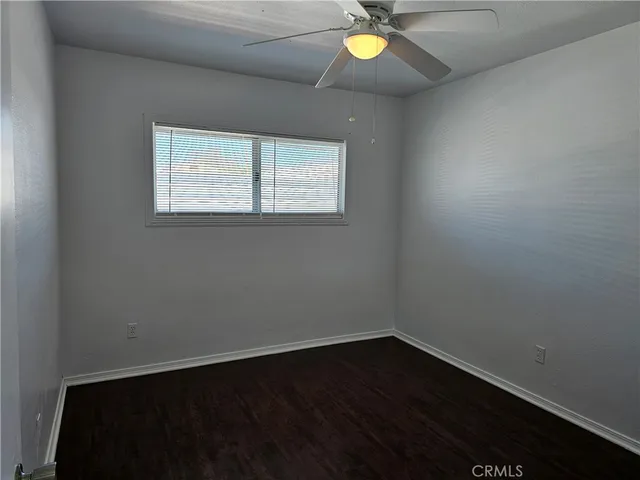 an empty room with wooden floor and ceiling fan