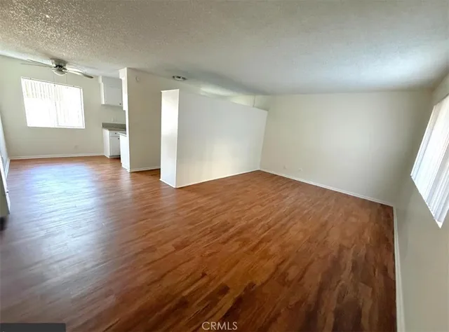 an empty room with wooden floor and windows