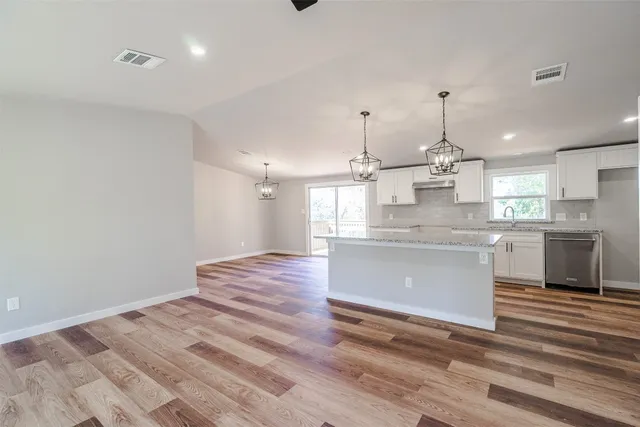 a kitchen with kitchen island white cabinets appliances and a chandelier