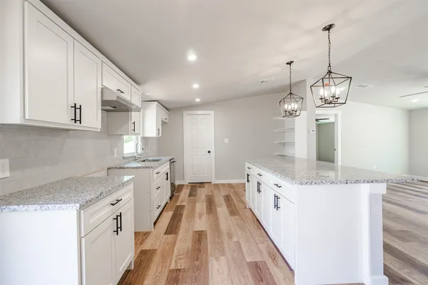 a kitchen with granite countertop a sink stove and white cabinets