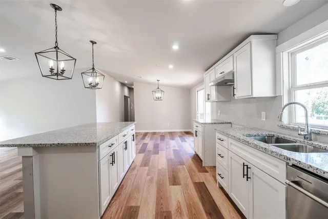 a large kitchen with kitchen island a stove a sink a center island and wooden floor