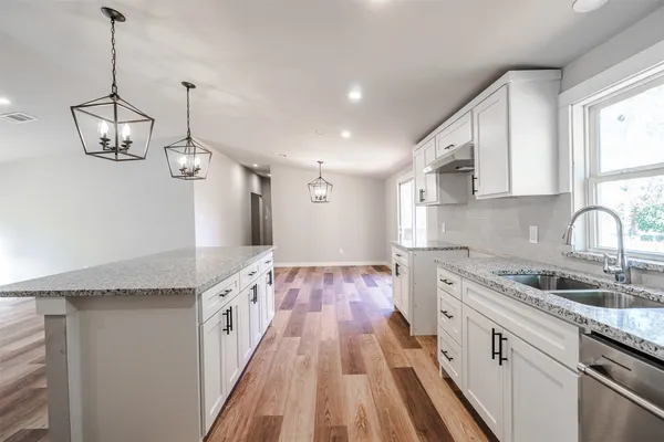 a kitchen with granite countertop a sink a counter space appliances and cabinets