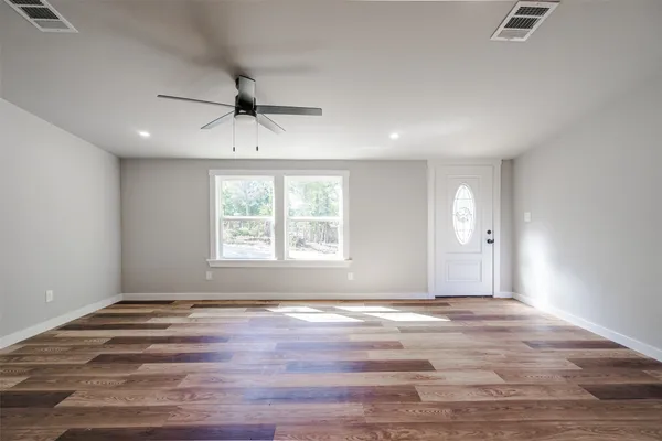 an empty room with windows and chandelier fan