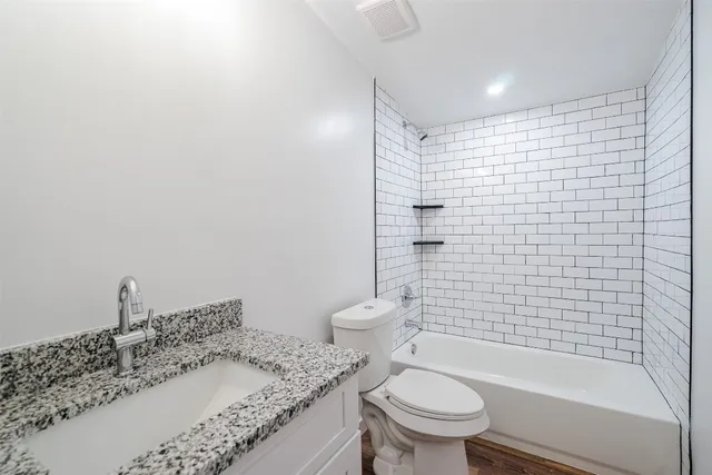 a bathroom with a granite countertop toilet a sink and a shower