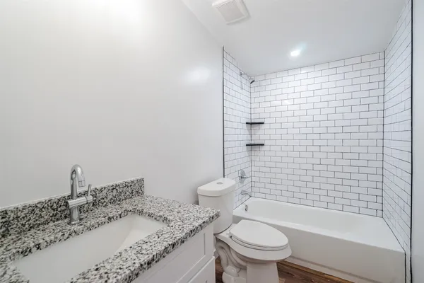 a bathroom with a granite countertop toilet a sink and a shower