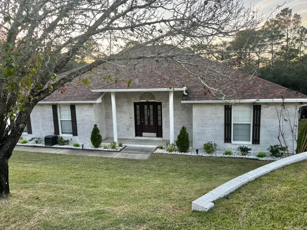 a front view of a house with a garden and trees