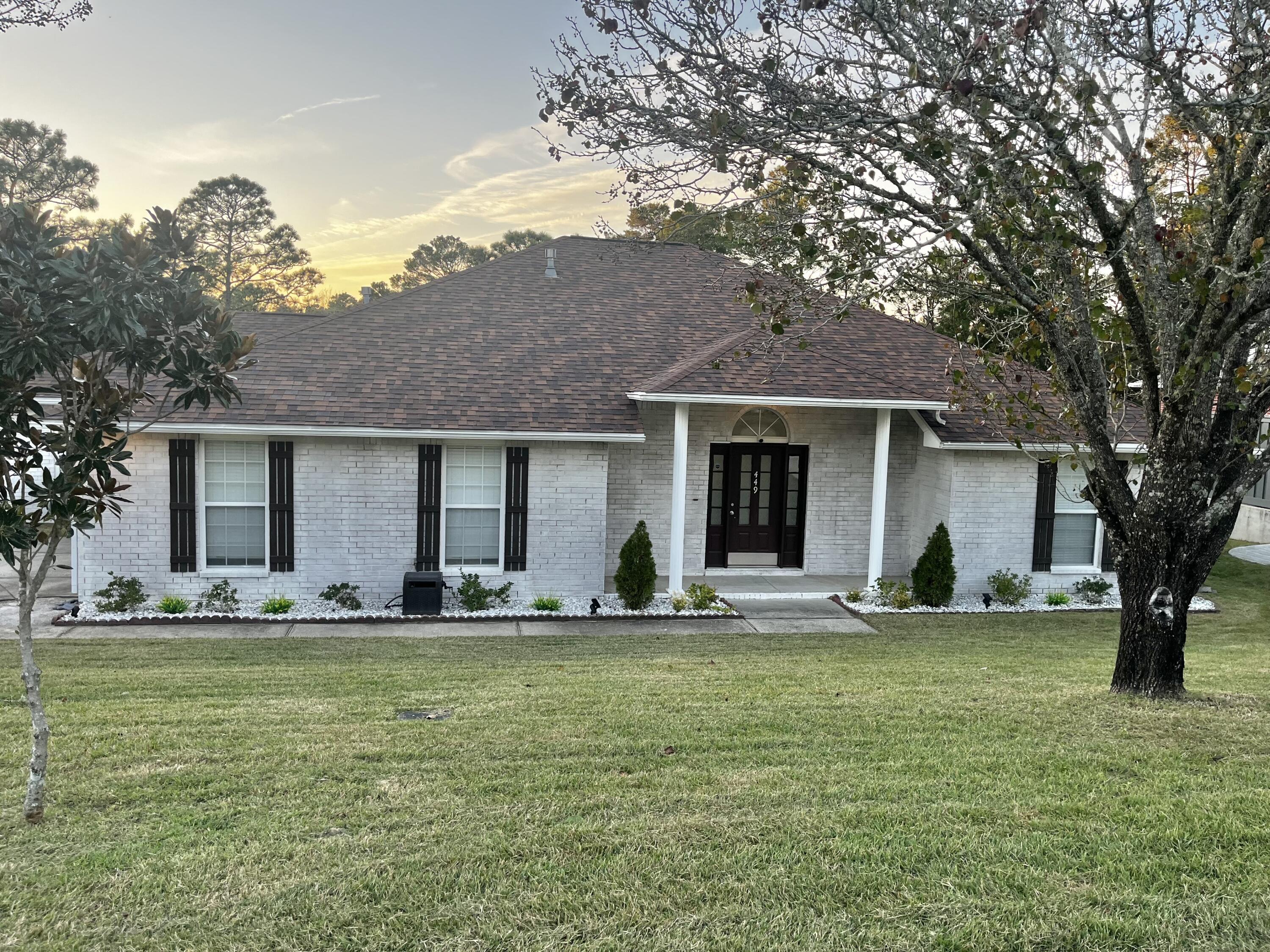 449 Ruckel Drive Niceville, FL 32578 - Photo 2 of 38 a front view of a house with a garden and trees