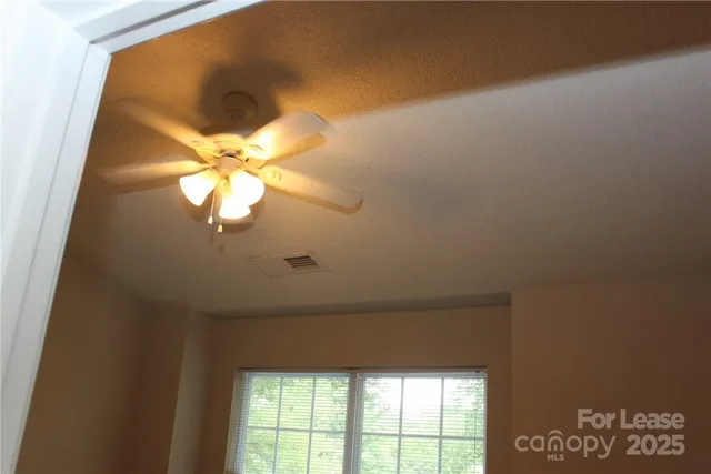 a view of a big room with wooden floor and chandelier fan