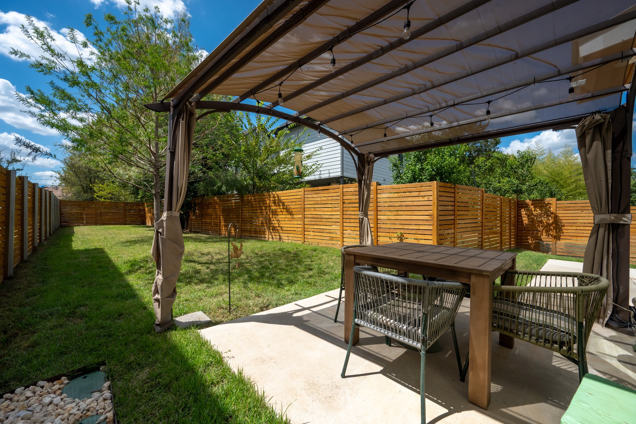 1190 Sarabeth Way Austin, TX 78721 - Photo 19 of 22 A concrete patio shaded by a canopy structure opens to a grassy backyard.